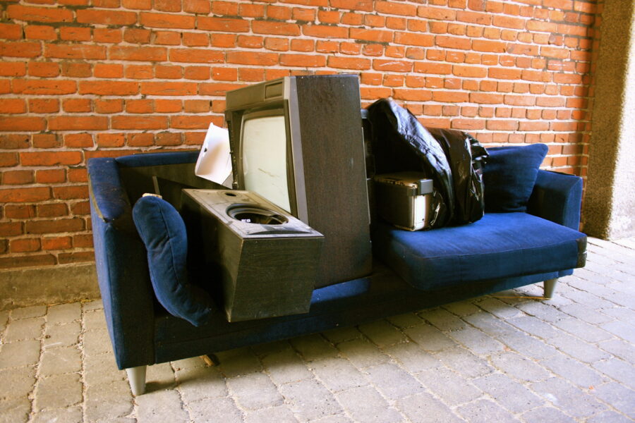 Old couch stacked with furniture in need of furniture removal services